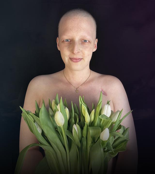 Sarah, eine der Protagonistinnen des 37GradLeben-Films "Krebskrank und Kinderwunsch?". Sie hat eine Glatze und hält einen Strauß weißer Tulpen vor ihre nackte Brust.