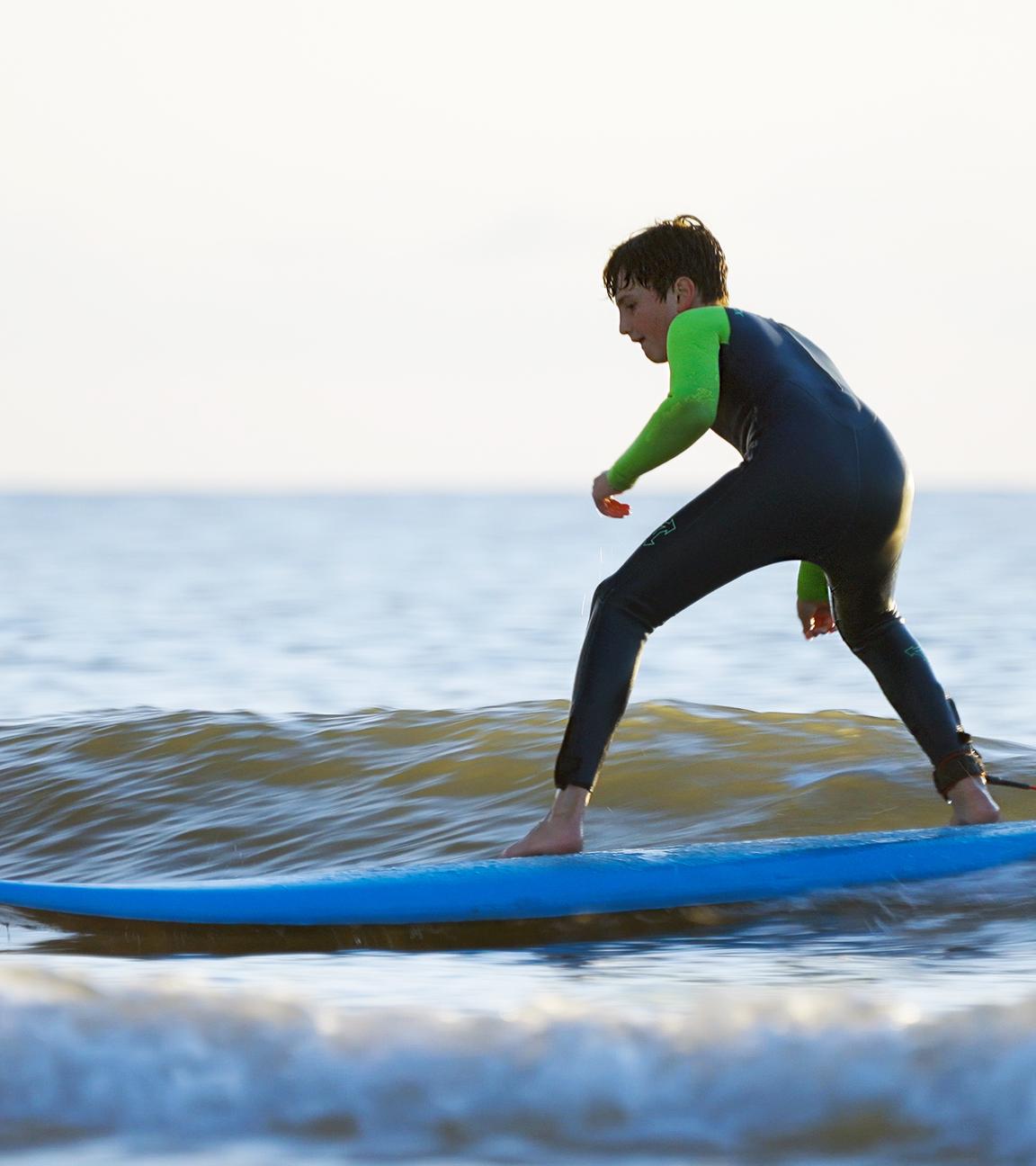 Junger Surfer auf dem Brett im Wasser.