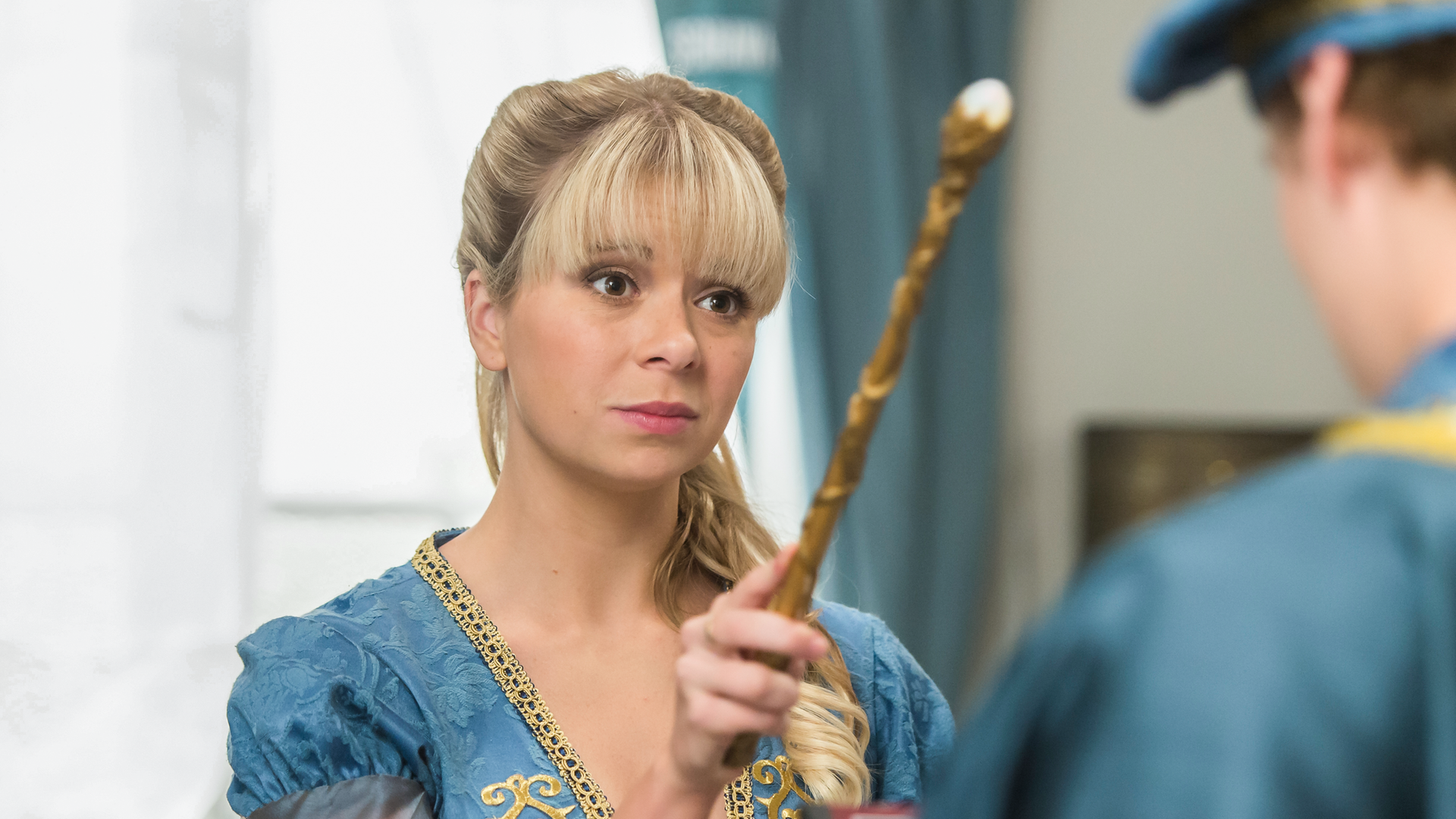 Lily steht vor Peter und hält einen Zauberstab in der Hand. Damit deutet sie in Peters Richtung.