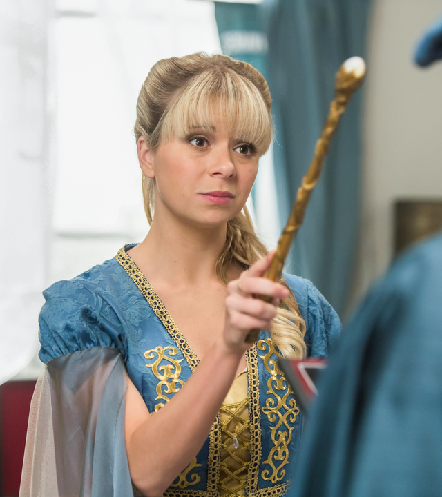 Lily steht vor Peter und hält einen Zauberstab in der Hand. Damit deutet sie in Peters Richtung.