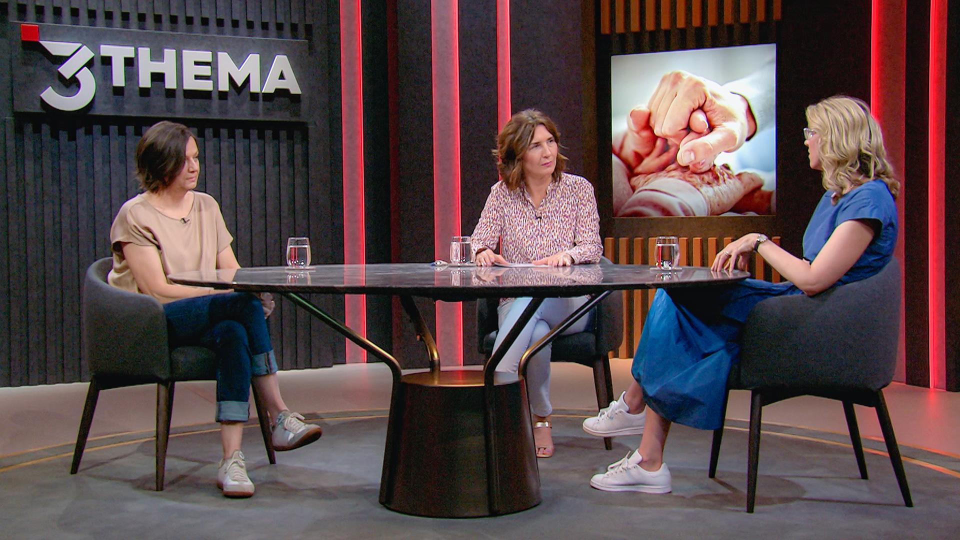 Drei Frauen sitzen im Studio an einem Tisch.