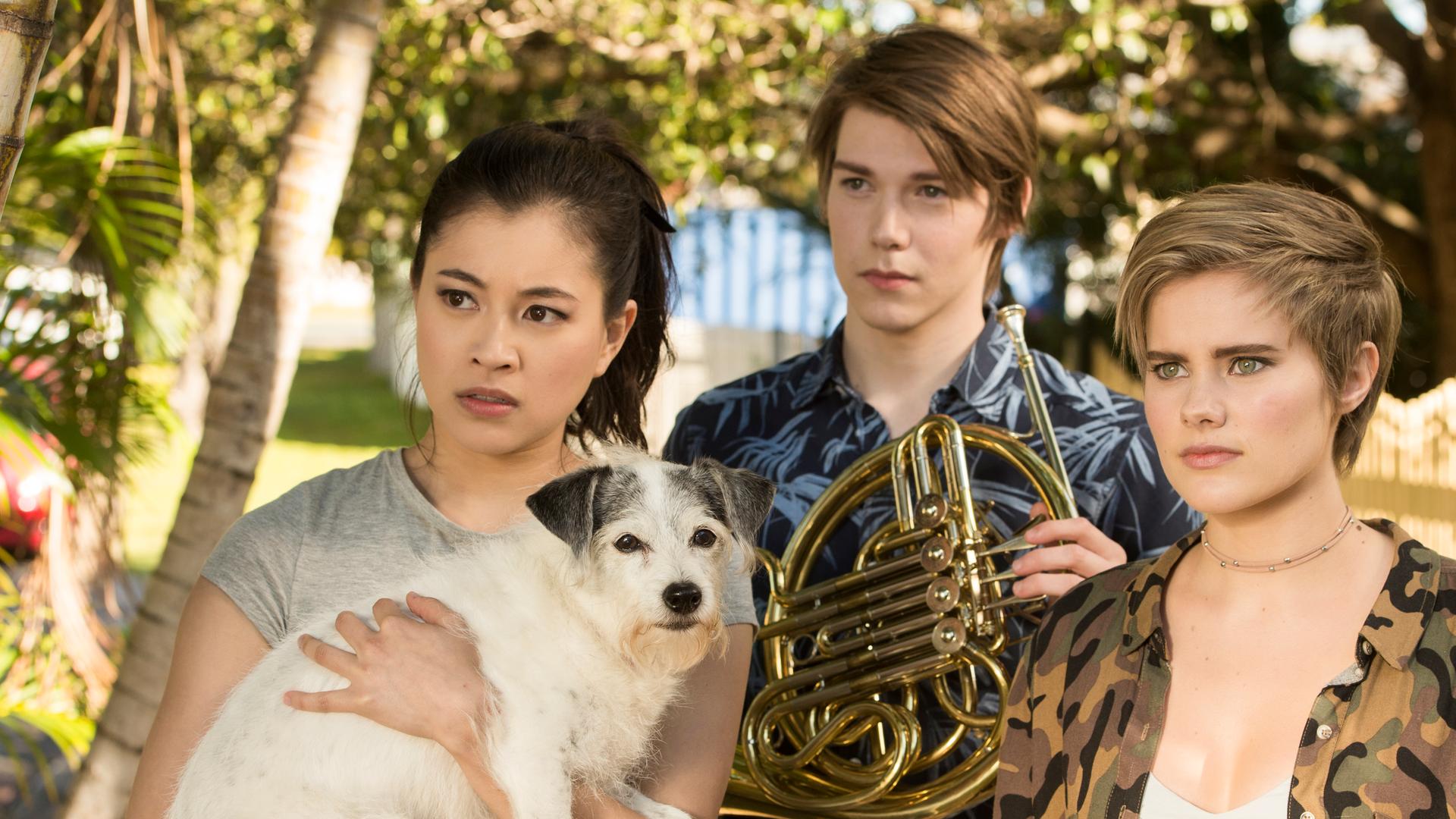 Kyra, Darra und Imogen schauen verwirrt. Kyra hat einen Hund auf dem Arm.