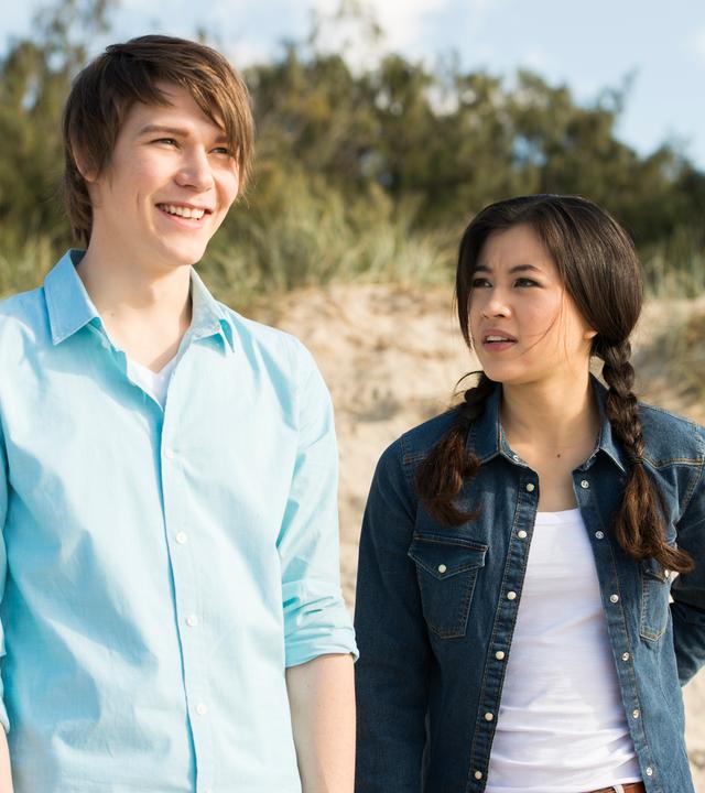 Darra (links) und Kyra (rechts) stehen am Strand. Darra lächelt.