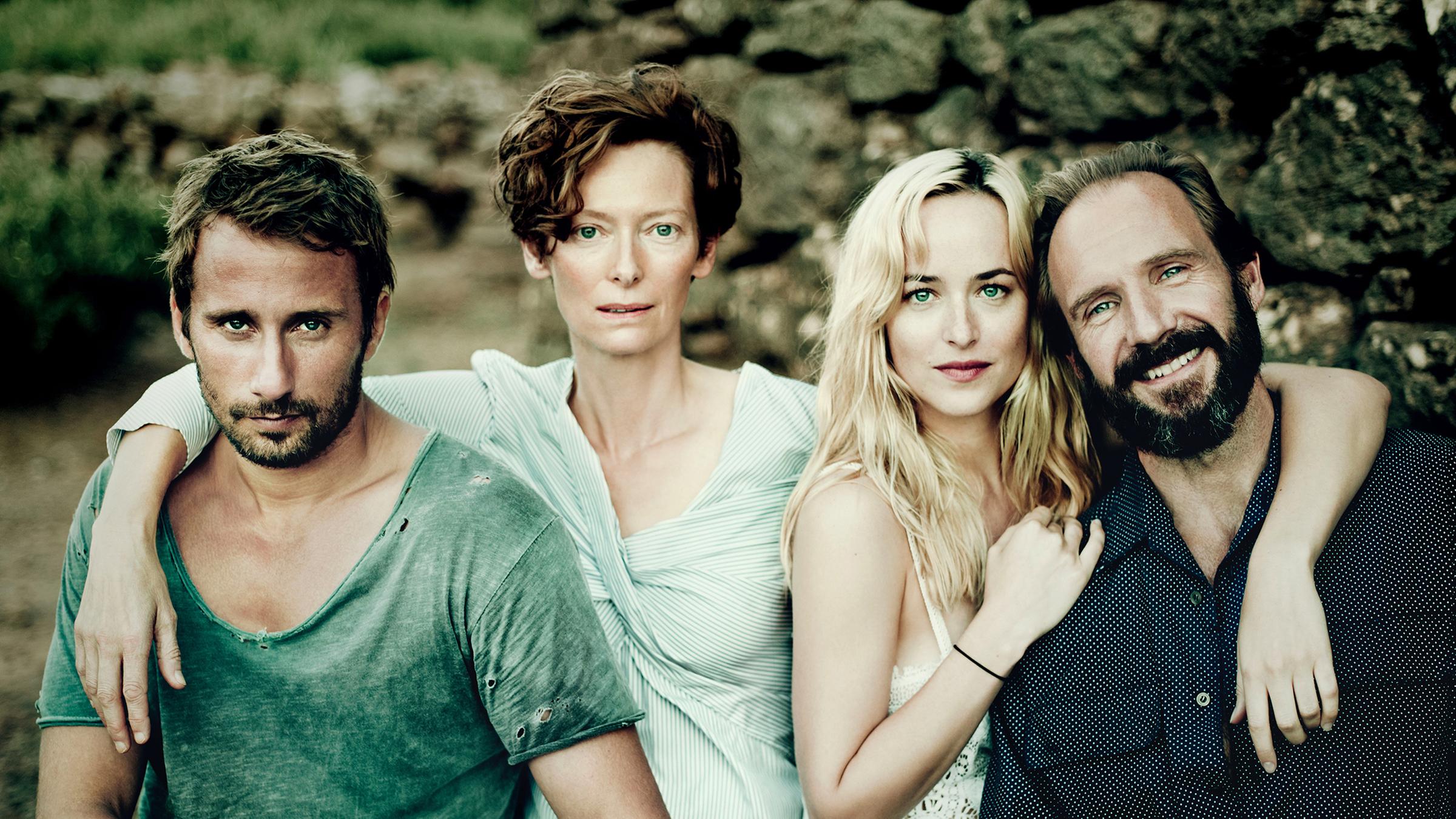 Paul (Matthias Schoenaerts), seine Geliebte Marianne (Tilda Swinton), die junge Penelope (Dakota Johnson) und ihr Vater Harry (Ralph Fiennes) sitzen nebeneinander und lächeln in die Kamera.