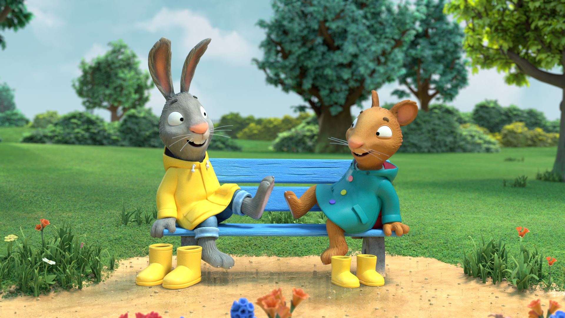Pip und Posy sitzen in ihren Regenmänteln auf einer Bank und klatschen sich mit ihren Füssen lachend ab. Vor der Bank stehen jeweils ein Paar gelbe Gummistiefel.