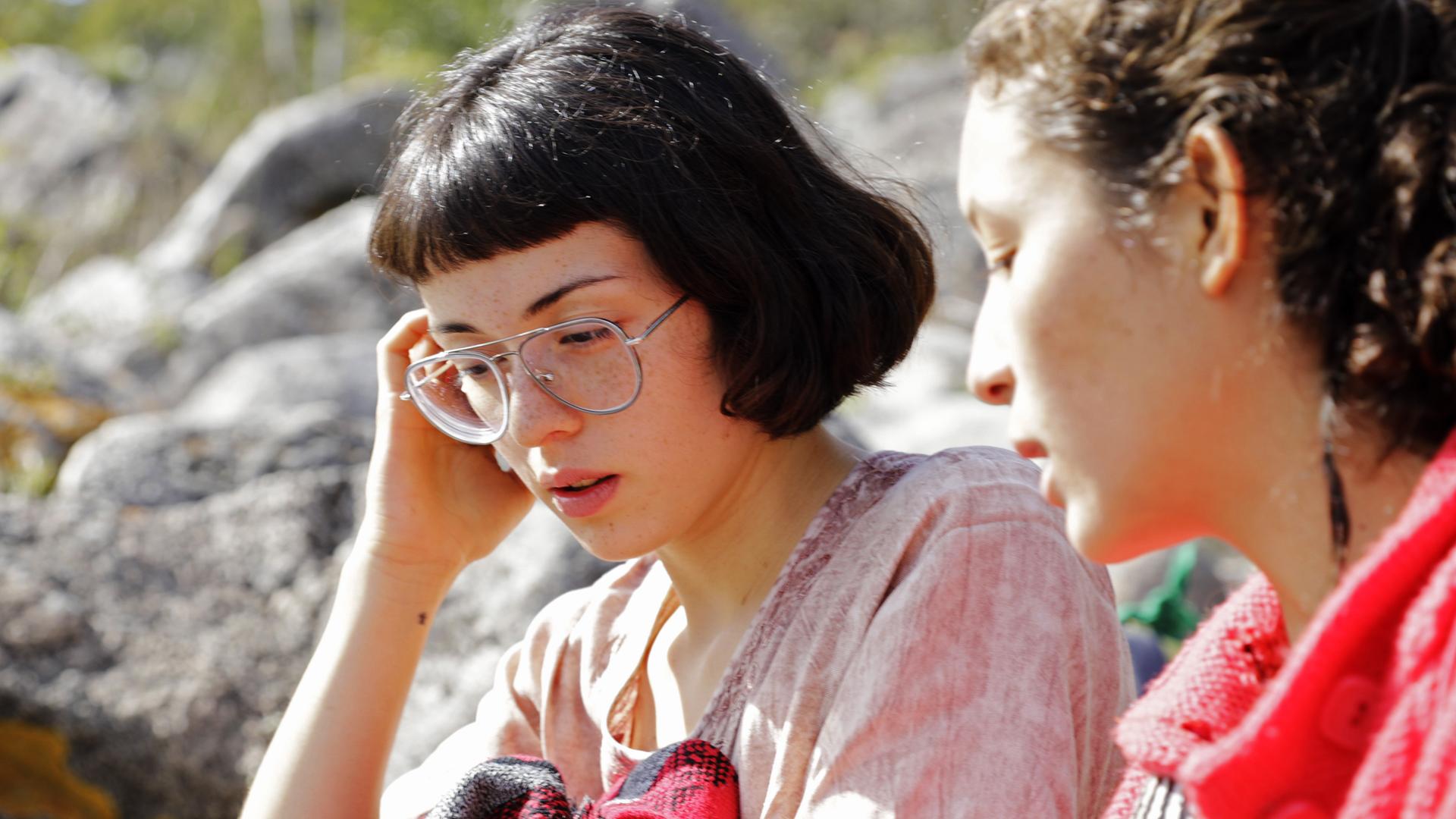 "Ab 18! Die Tochter von": Zwei dunkelhaarige Mädchen sitzen gemeinsam am Ufer eines Flusses.
