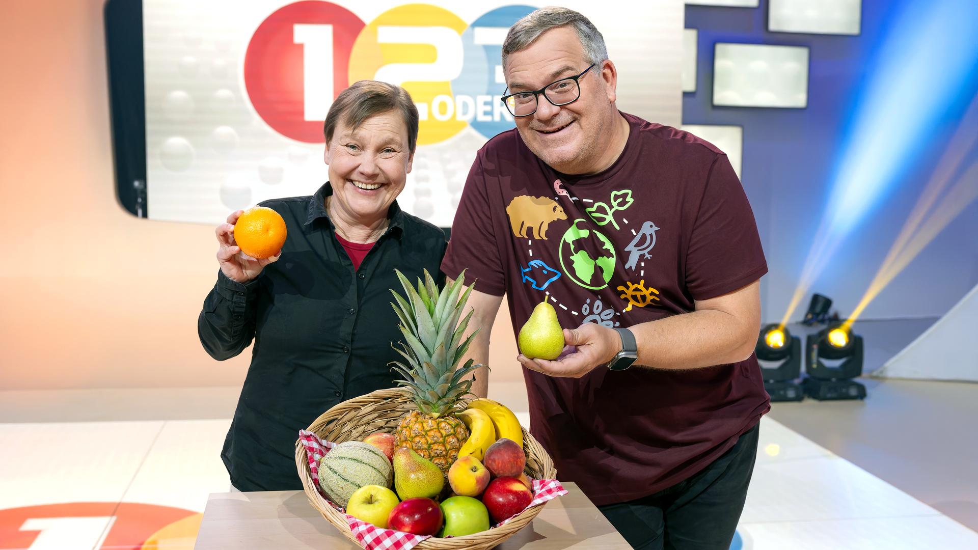 Elton und Jessica Freiherr halten lächeln Obst in die Kamera.
