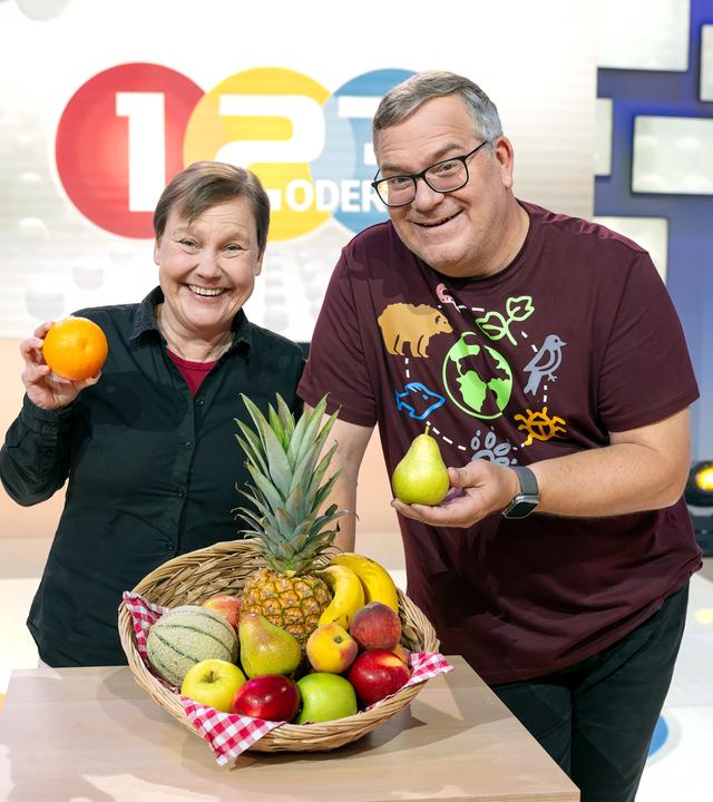 Elton und Jessica Freiherr halten lächeln Obst in die Kamera.