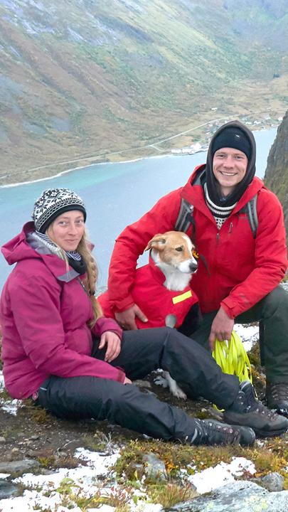 Ellen und Jonas sitzen mit Hund Suki auf dem verschneiten Gipfel des Husfjellet auf der Insel Senja in Norwegen.