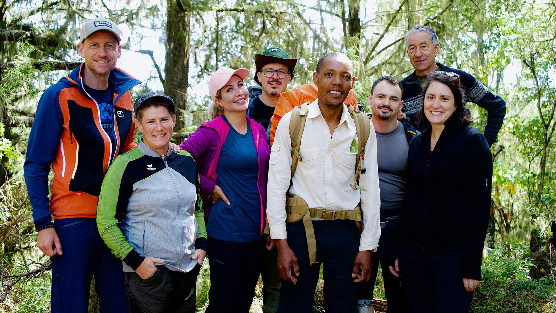 Acht Personen in Trekkingausrüstung posieren für ein Gruppenbild