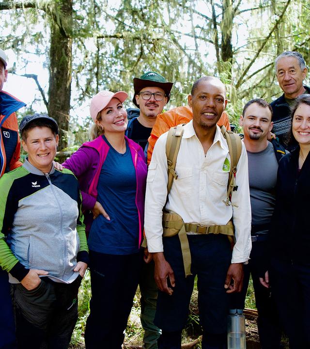 Acht Personen in Trekkingausrüstung posieren für ein Gruppenbild