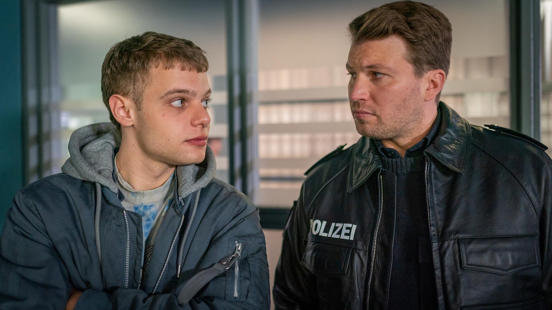 "Notruf Hafenkante - Abgestürzt": Großaufnahme von Timo Quandt (Lennart Herrmann) und Nick Brandt (Raúl Richter). Sie stehen dicht nebeneinander und sehen sich an.