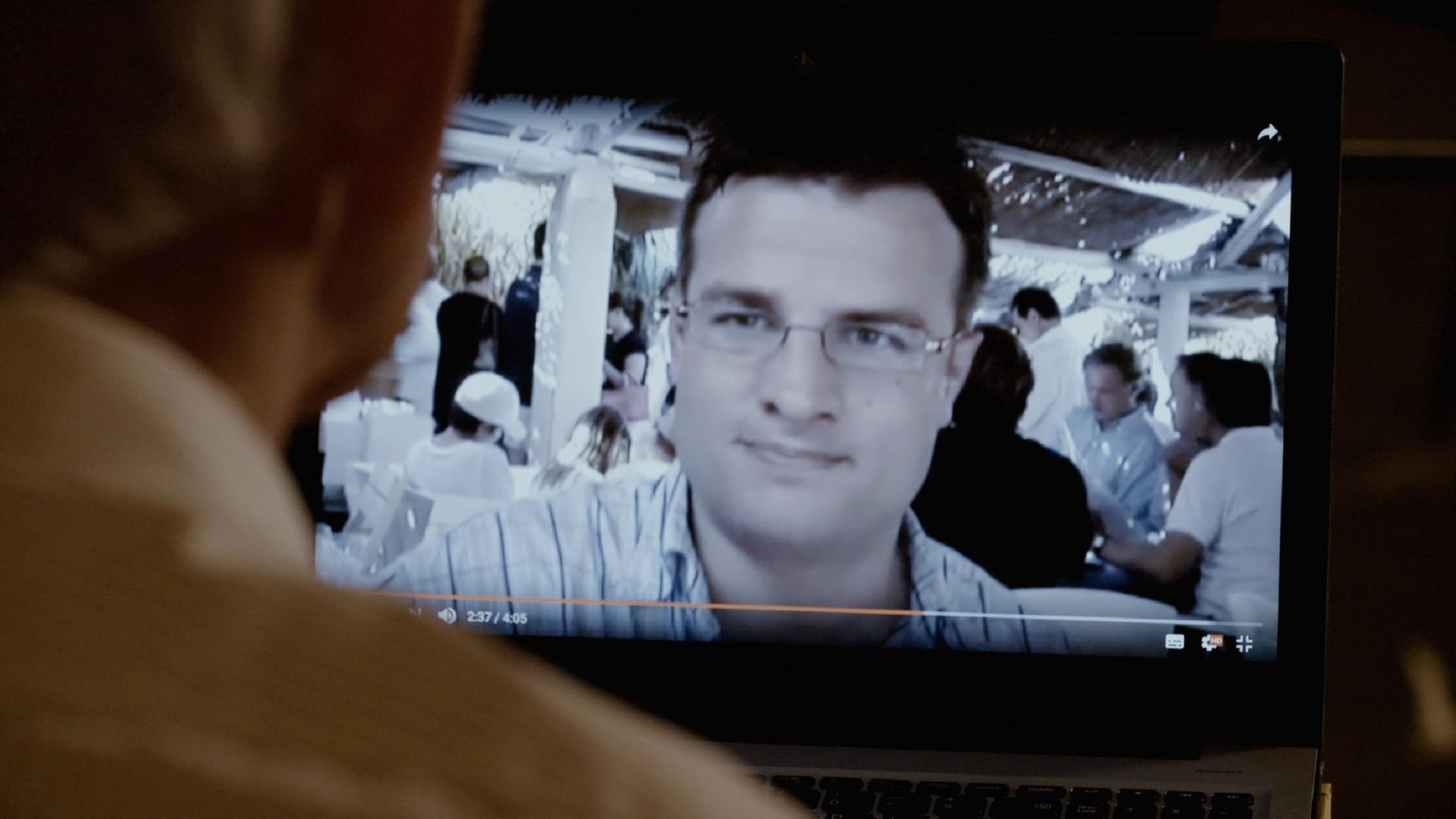 "Abgezockt! Der Anlagebetrüger Felix Vossen": Eine Person, die nur von hinten im Anschnitt zu sehen ist, schaut auf einen Computerbildschirm, auf dem Felix Vossen abgebildet ist.