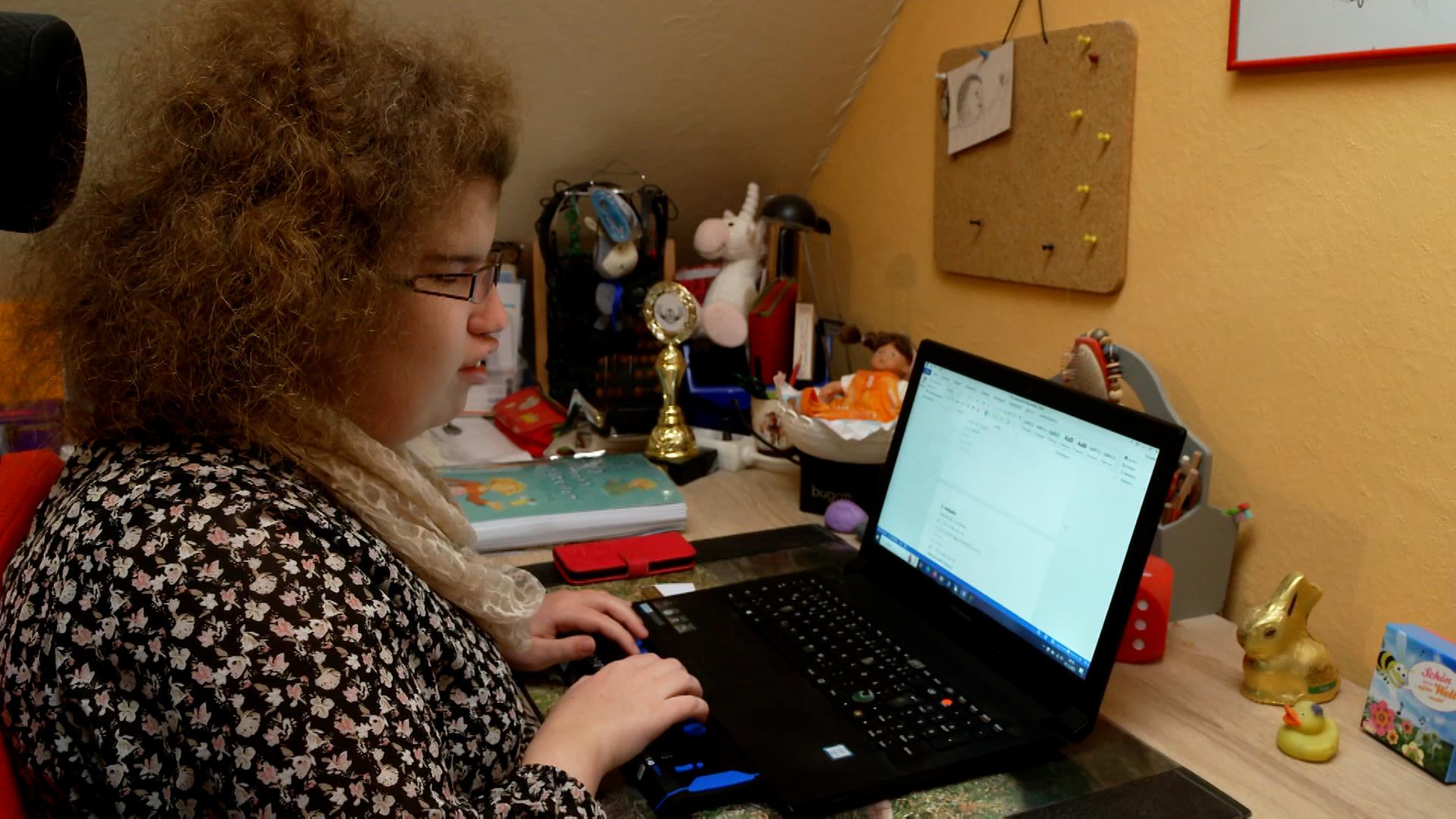 Tabea Tams ist seit Geburt an blind und macht dennoch ihr Abitur. Im Bild sitzt sie am Schreibtisch und arbeitet an einem Laptop.