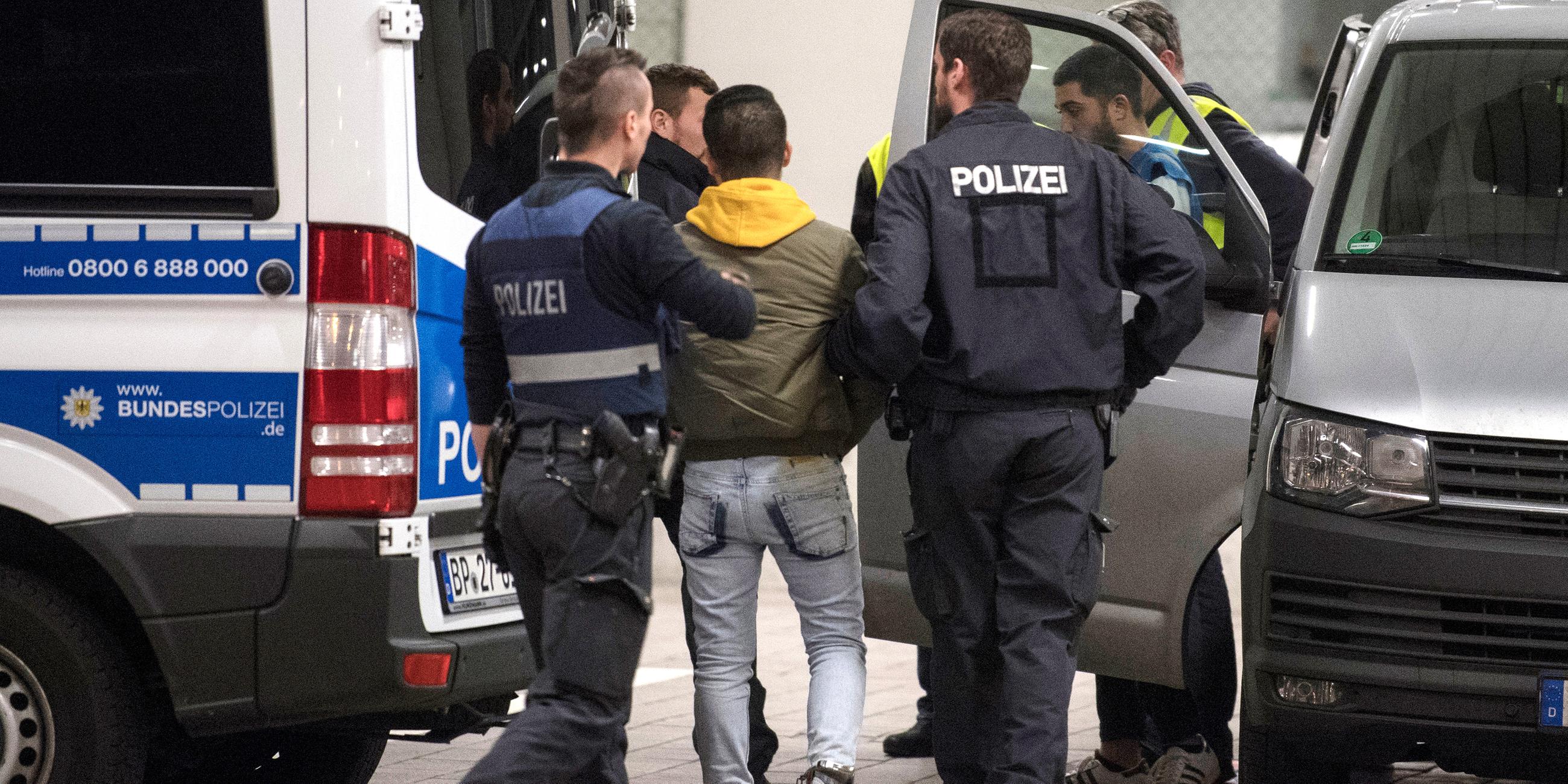 Hand und Fussfesseln trägt ein junger Mann aus Afghanistan, den Polizisten zur Abschiebung zum Flughafen bringen, aufgenommen am 04.12.2018 in Frankfurt am Main