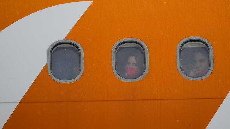 Aus den Vereinigten Staaten abgeschobene venezolanische Migranten schauen nach der Landung aus den Bullaugen ihres Flugzeugs.