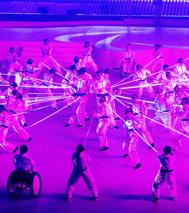 Künstler performen während der Abschlussfeier der Paralympics unter rosafarbenem Licht.