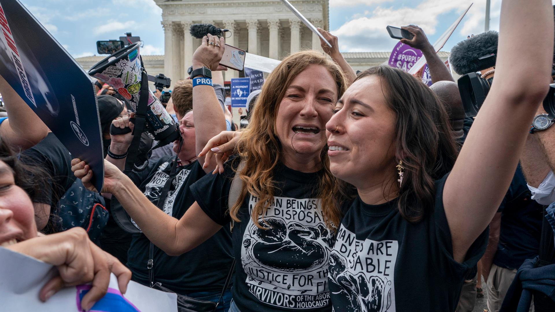 Zwei Frauen liegen sich lachend in den Armen