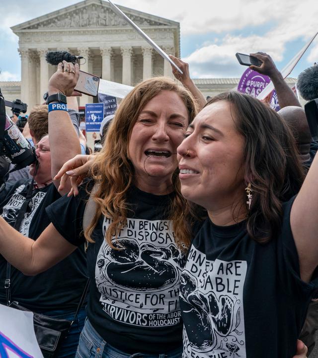 Zwei Frauen liegen sich lachend in den Armen