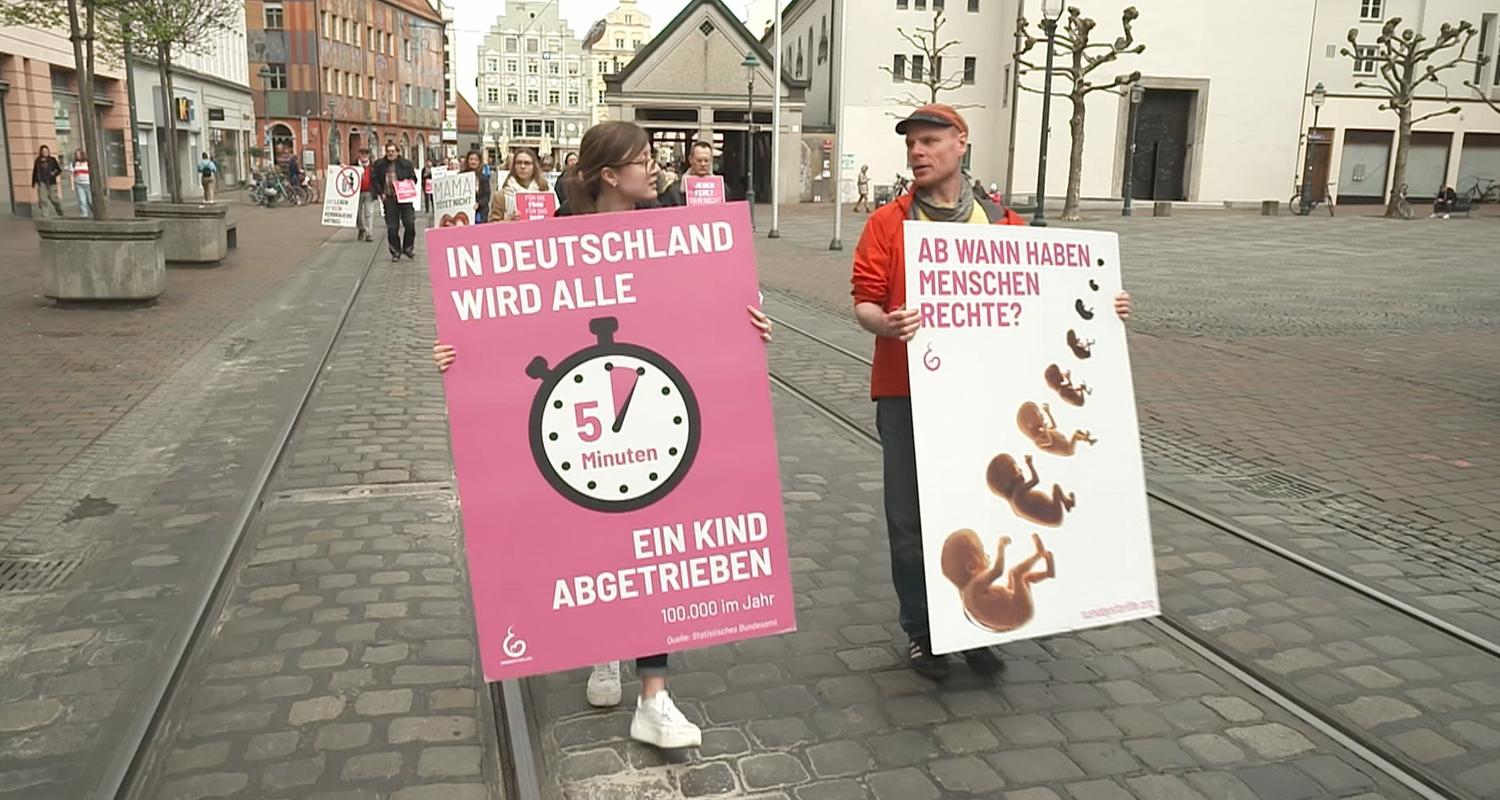 Zwei Demonstranten, links Frau, rechts Mann, mit Plakaten "In Deutschland wird alle 5 Minuten ein Kind abgetrieben" "Ab wann haben Menschen Rechte?"