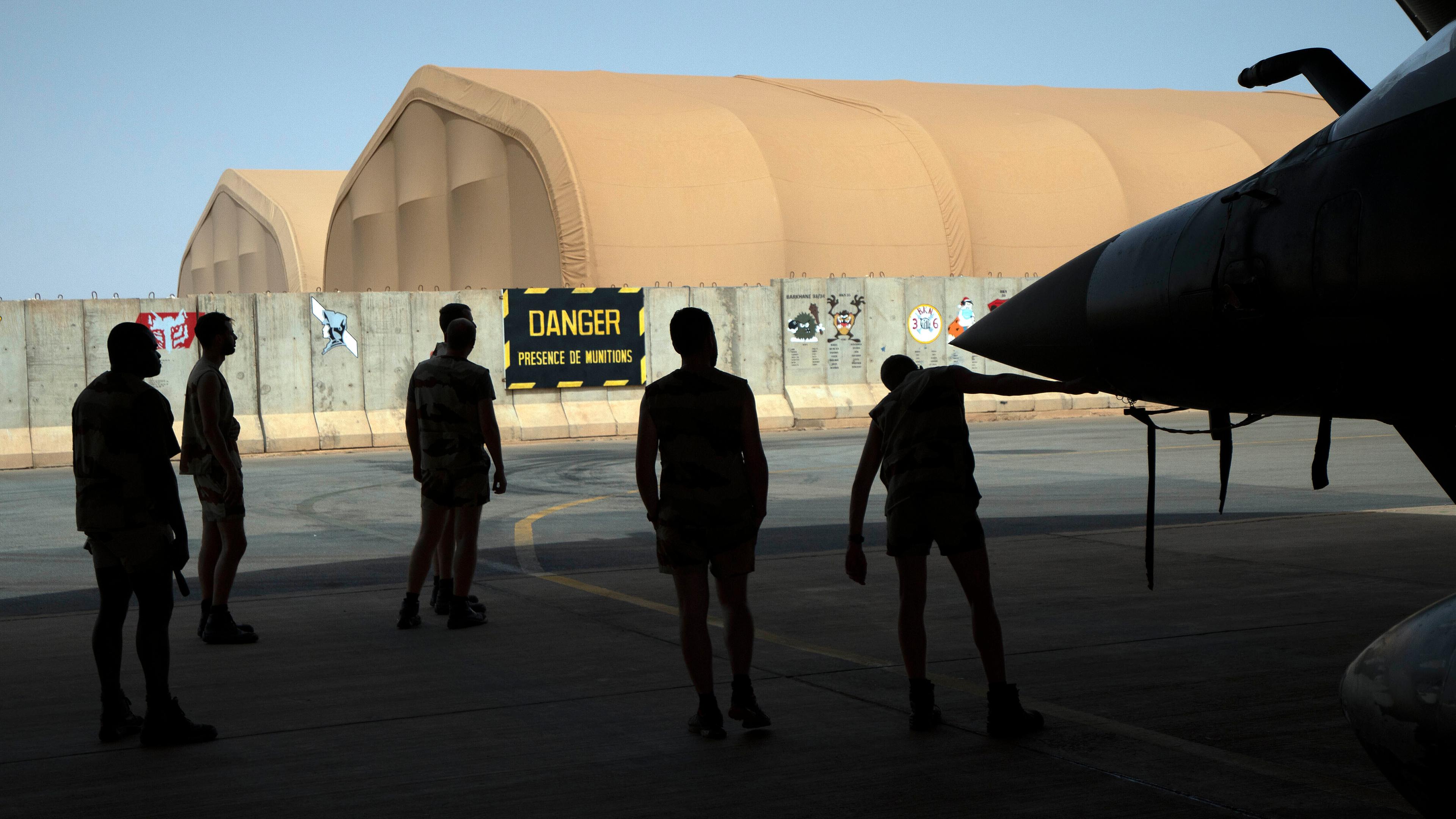 Französische Soldaten der Luftwaffe stehen neben einem Kampfjet in einem Hangar