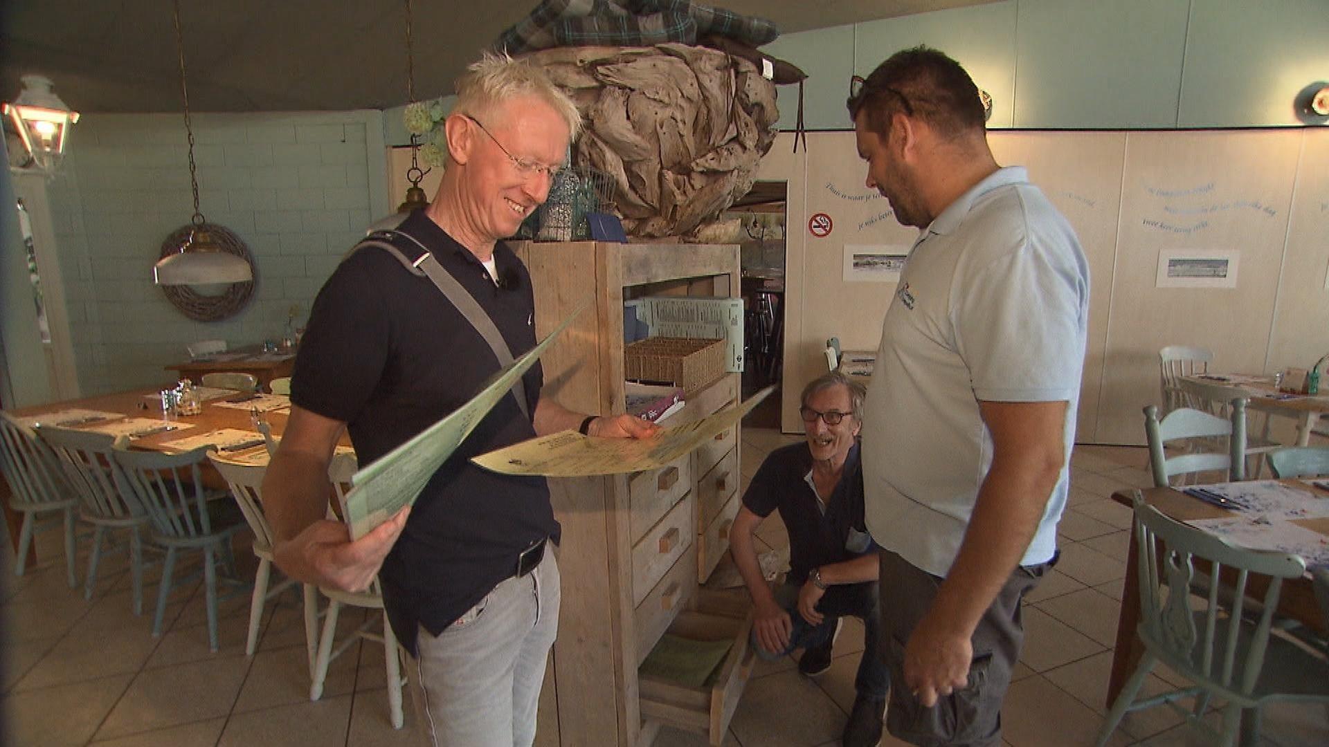 "Achtung, Camper! Die Jagd nach guten Bewertungen": ADAC-Inspekteur Kai Wentz betrachtet im Restaurant eines Campingplatzes die Speisekarte. Zwei weitere Männer sind bei ihm.