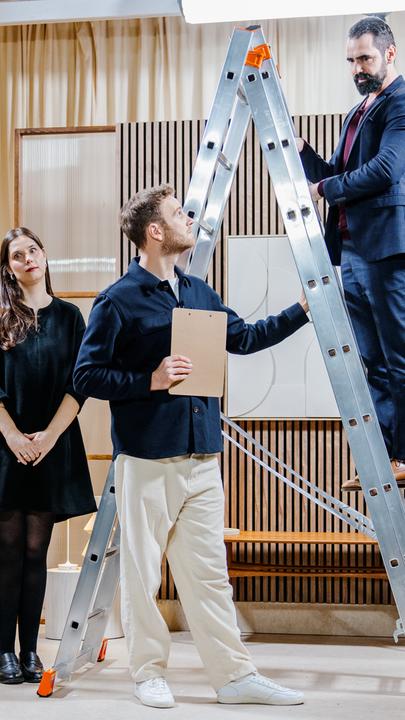 Ozan Taş auf einer Leiter, Dr. Leon Windscheid und Tara-Louise Wittwer daneben