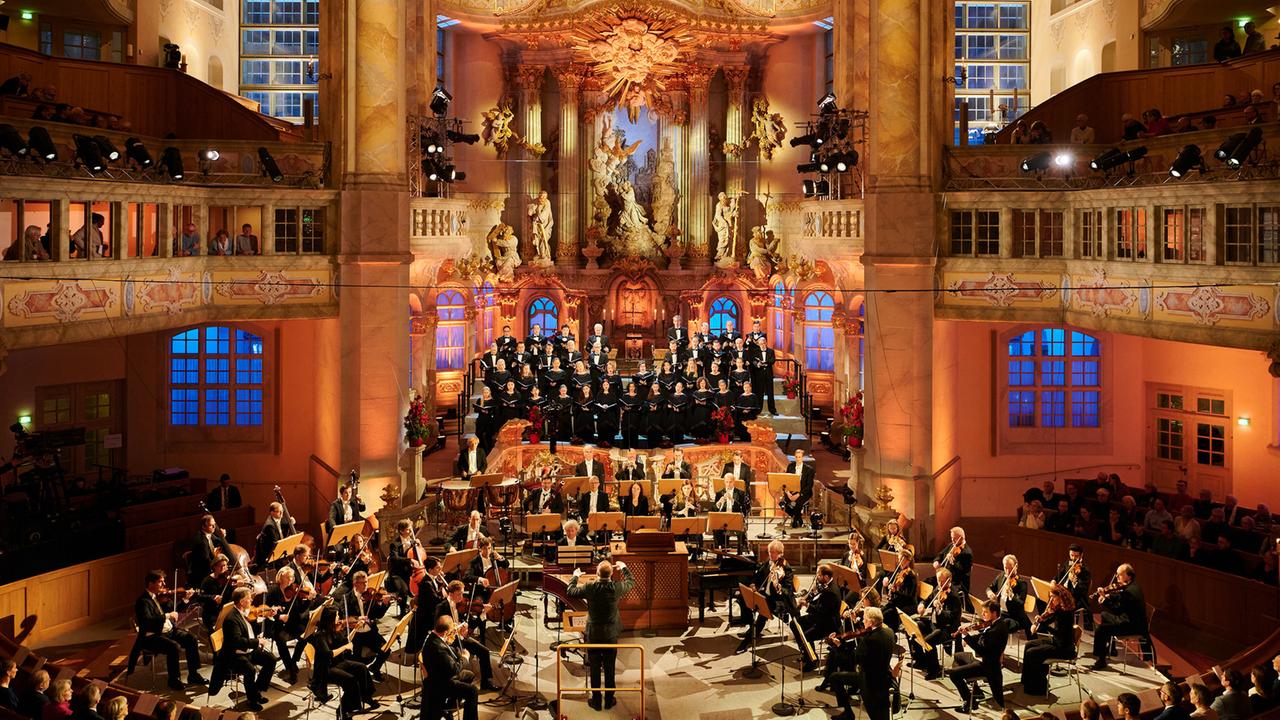 "Adventskonzert aus Dresden": Außenaufnahme der Frauenkirche in Dresden: Blick von unten an der Frauenkirche empor in den nächtlichen Himmel. An der Seite steht ein geschmückter Weihnachtsbaum.