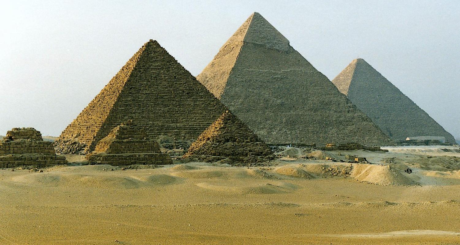 Blick auf die Pyramiden von Gizeh vor klarem, hellblauem Himmel.