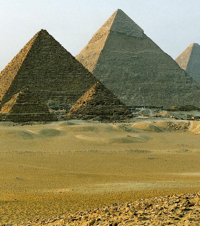 Blick auf die Pyramiden von Gizeh vor klarem, hellblauem Himmel.
