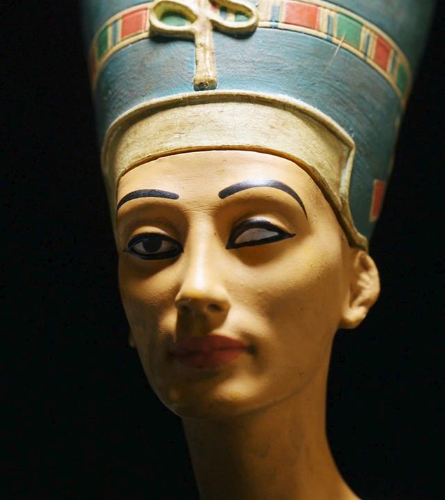 Viertelprofil der Büste der Nofretete vor schwarzem Hintergrund. Auffällig ist die fehlende Einlage des linken Auges.