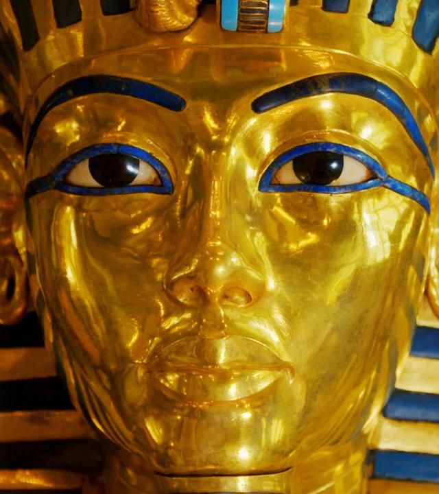 Nahaufnahme der Totenmaske des Tutanchamun. Die goldene Maske ist mit blauen Halbedelsteinen verziert.