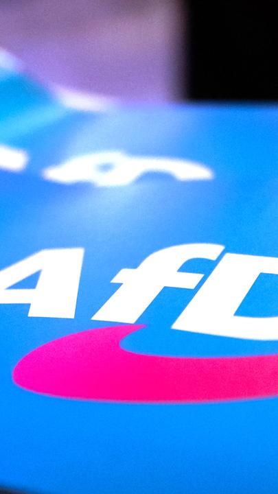 Fähnchen mit dem Logo der AfD liegen auf einem Tisch.