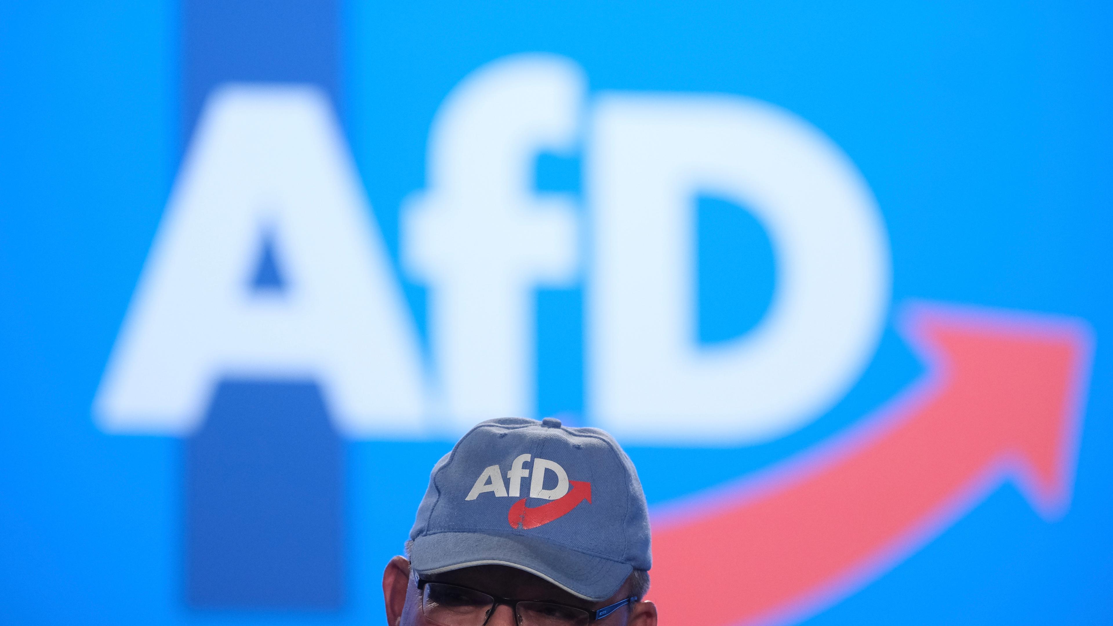 Eine AfD-Kappe vor einem großen Afd-Logo an der Wand
