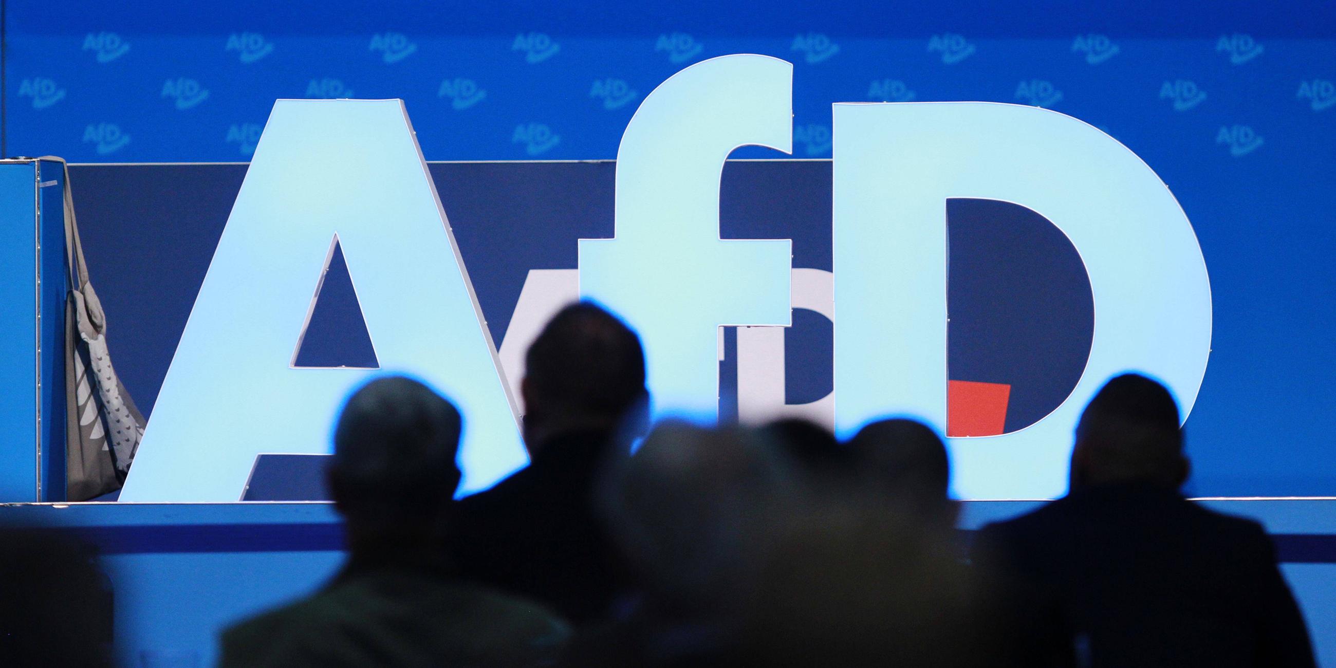 Symbolbild: AfD-Logo, davor Delegierte