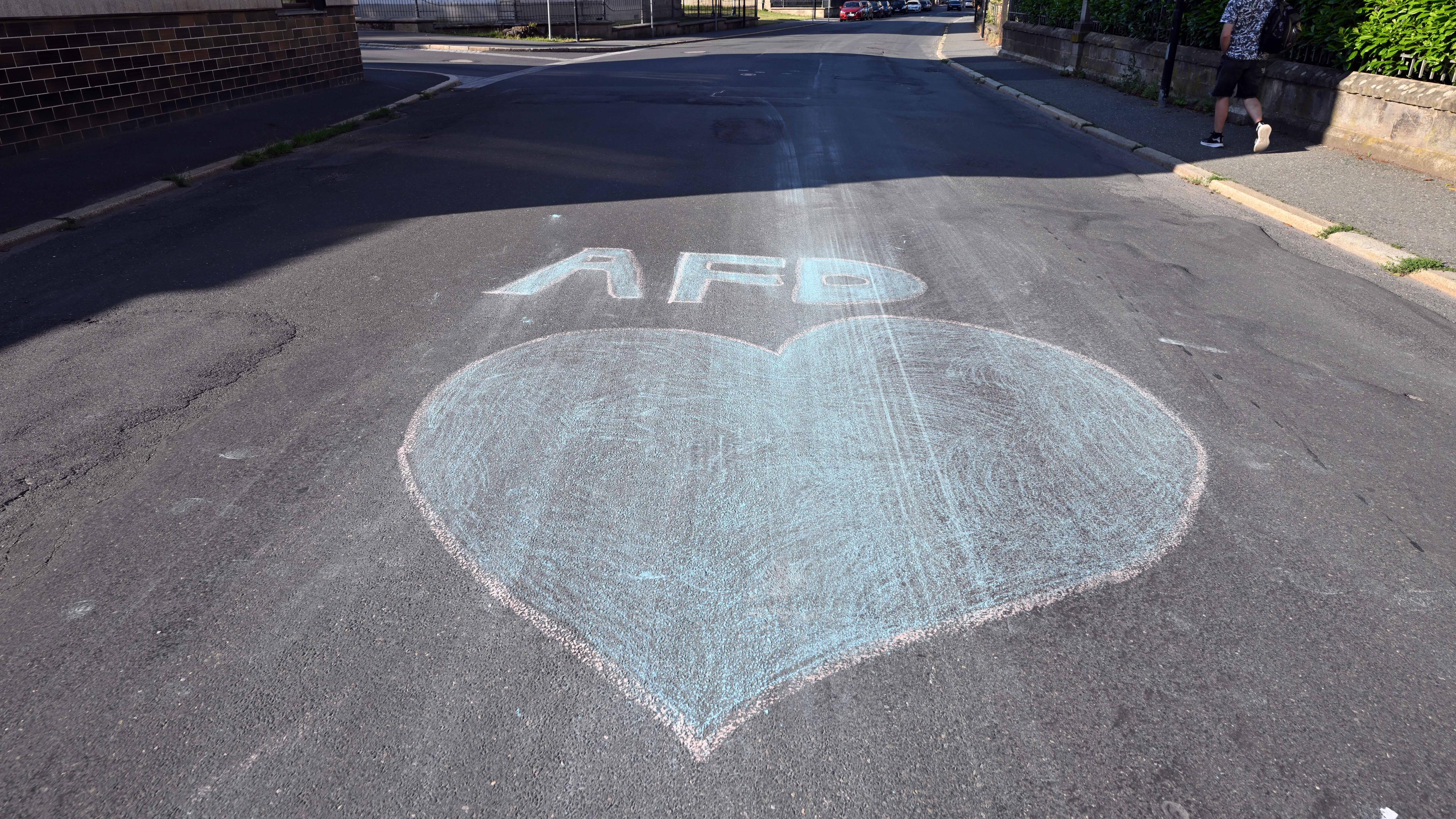 Ein blaues Herz und der Schriftzug AfD sind mit Kreide auf eine Straße gemalt am Tag der Stichwahl des Landrats im Landkreis Sonneberg.