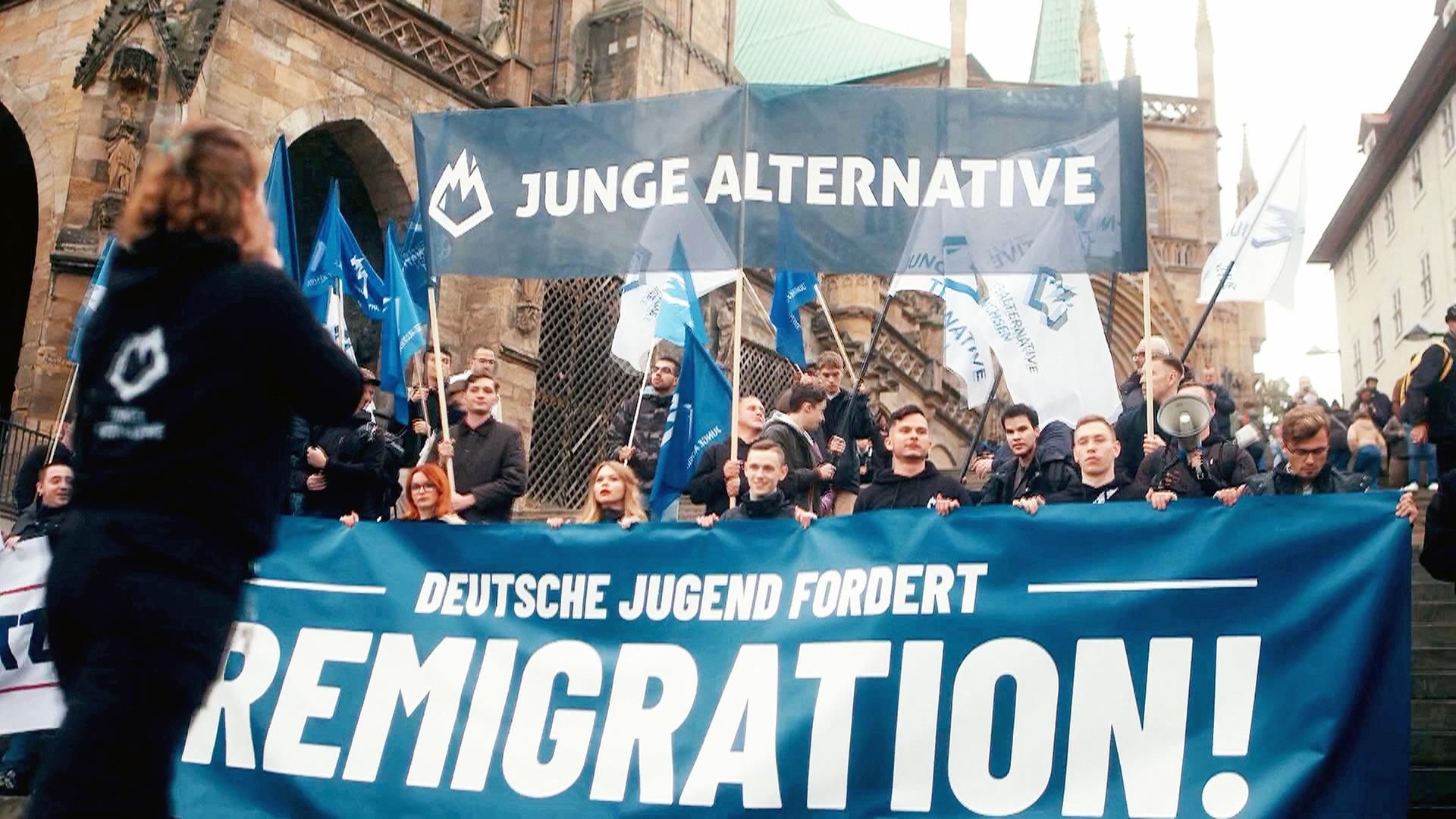 Demo "Junge Alternative", Teilnehmer mit Banner: "Deutsche Jugend fordert Remigration!"