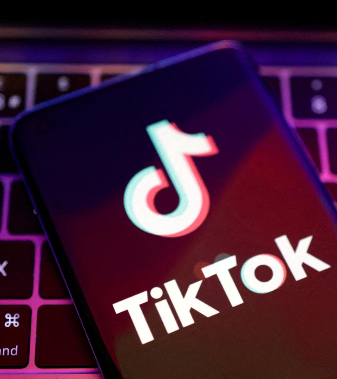 Ein Smartphonebildschirm mit dem Logo von TikTok liegt auf einer Computertastatur.