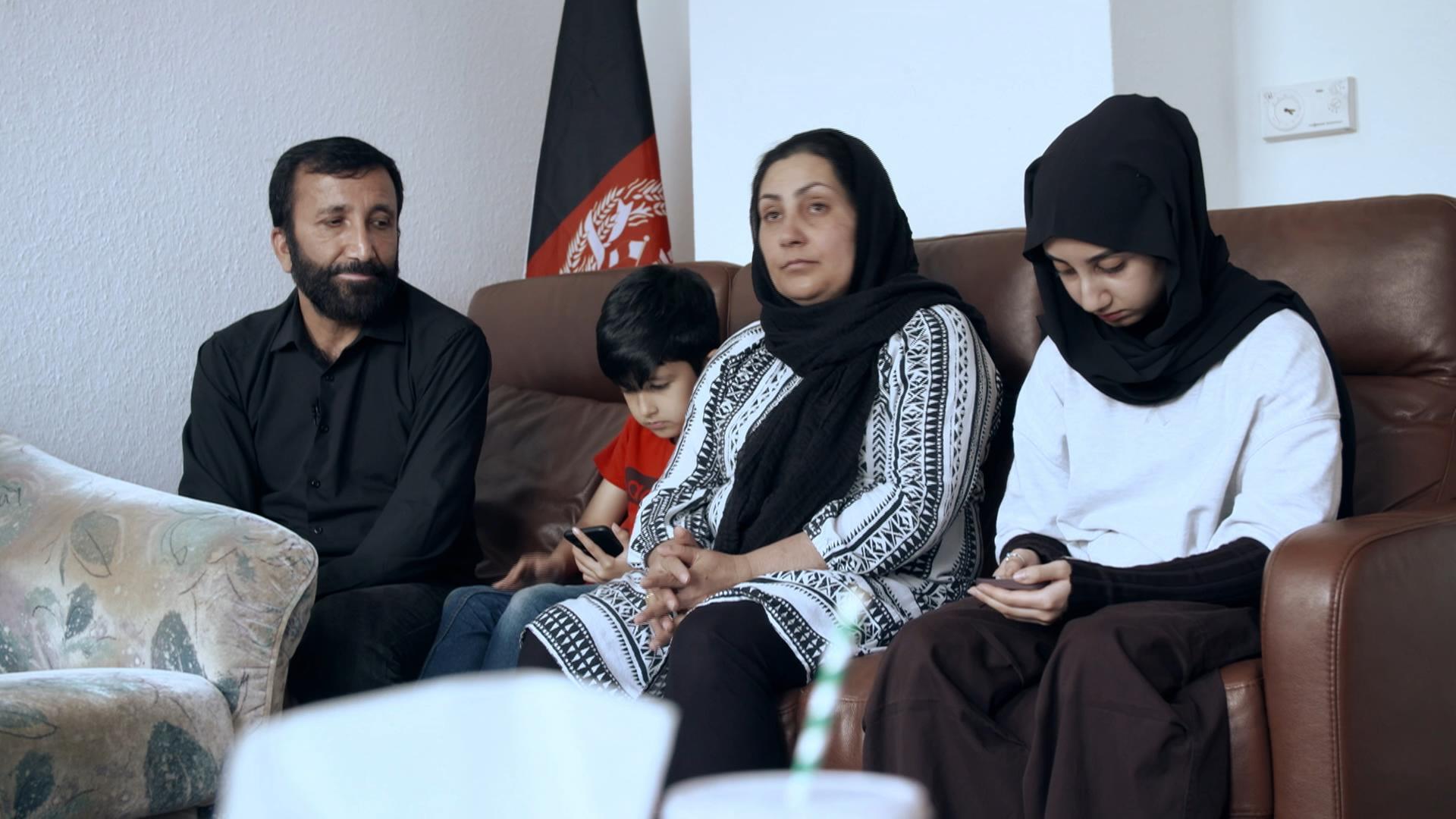 Vater, Sohn, Mutter und Tochter sitzen auf dem Sofa