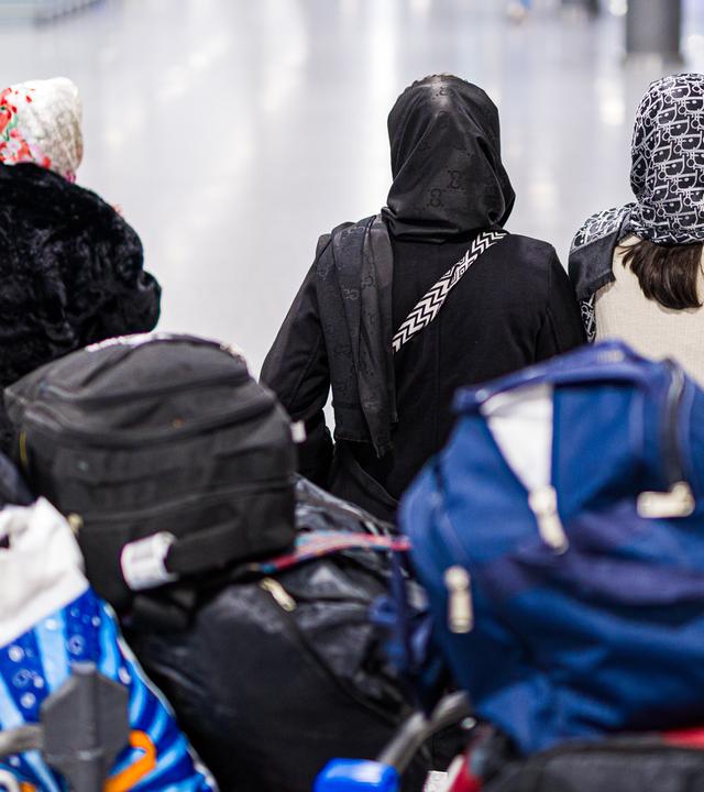 Menschen aus Afghanistan, die zuvor mit einem Flugzeug auf dem Flughafen Hannover-Langenhagen gelandet sind, verstauen ihr Gepäck in einem Anhänger. Die afghanische Staatsangehörige haben eine Aufnahmezusage für Deutschland.