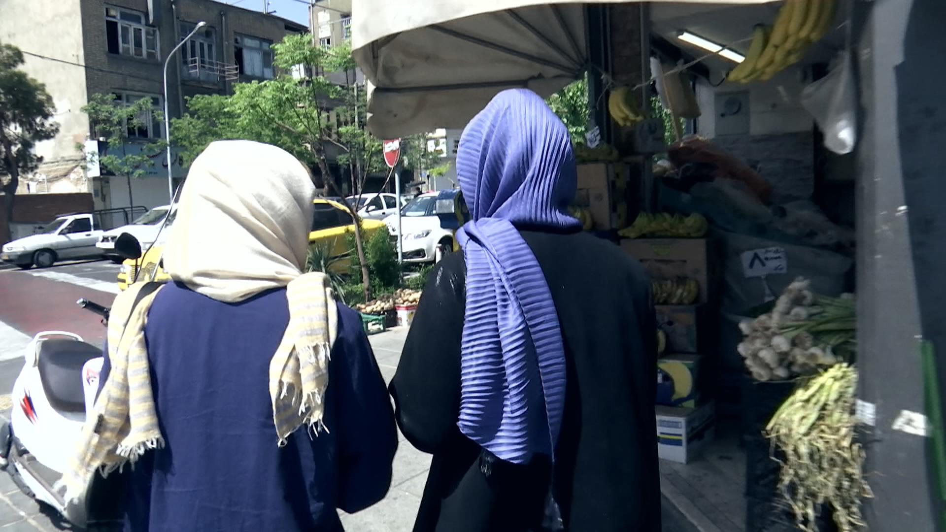 Zwei Frauen mit Kopftuch laufen Straße entlang
