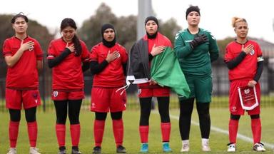 Mehrere afghanische Fußballerinnen auf dem Platz bei der Hymne.