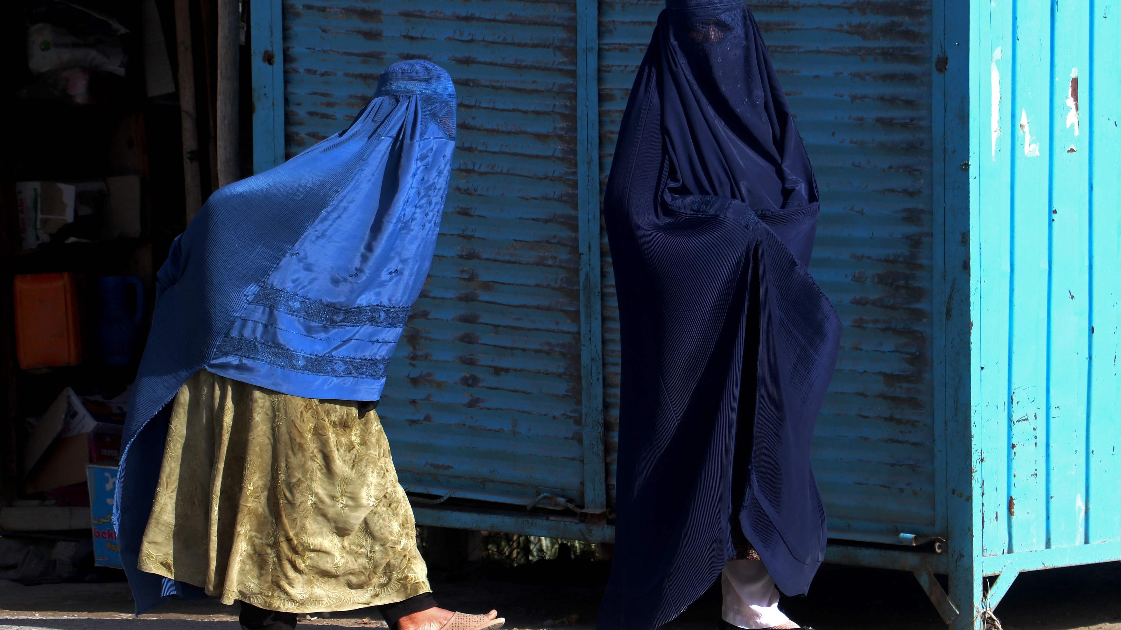 fghan burqa-clad women walk along a road in Fayzabad district of Badakhshan province on August 8, 2023.