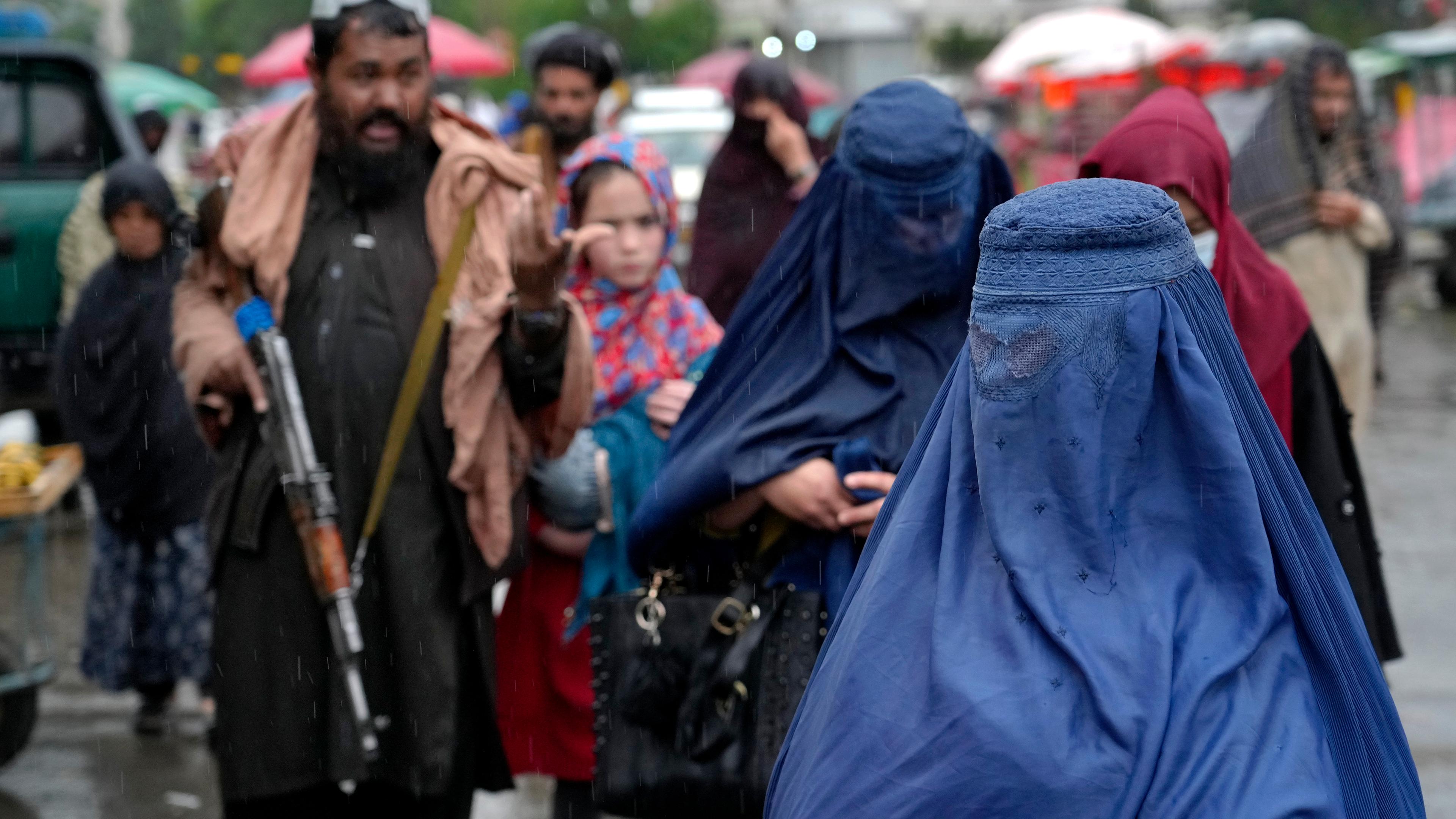 Afghanistan, Kabul: Frauen gehen an der bewaffneten Taliban-Wache vorbei.