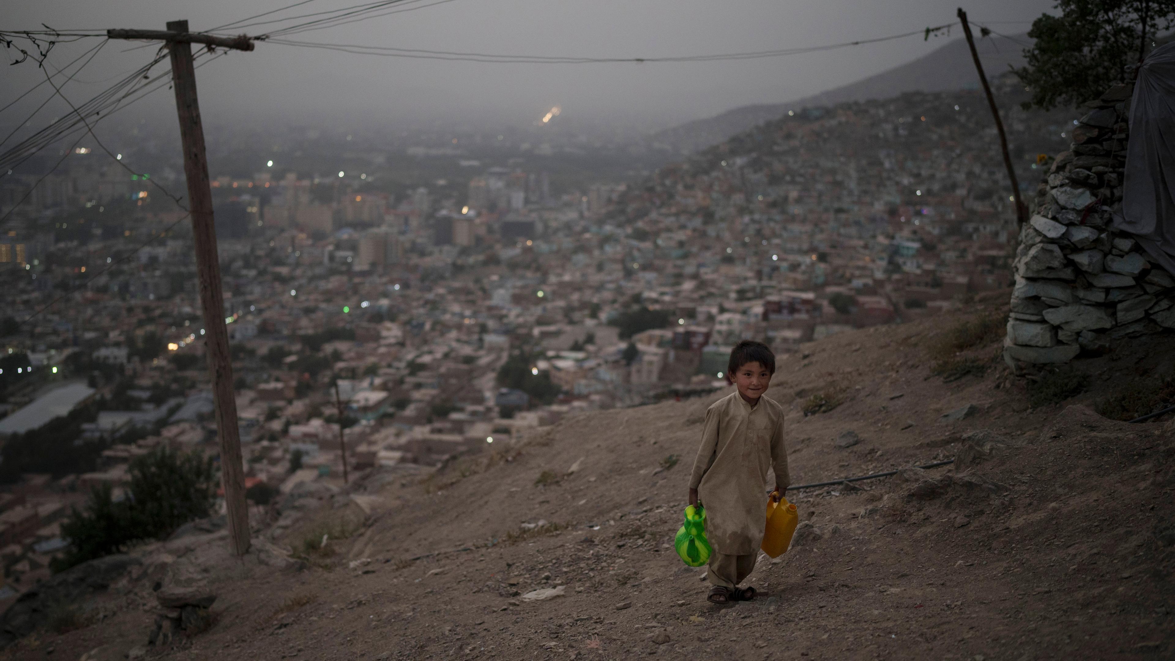 Junge trägt Wasserkanister in einem Slum in Kabul