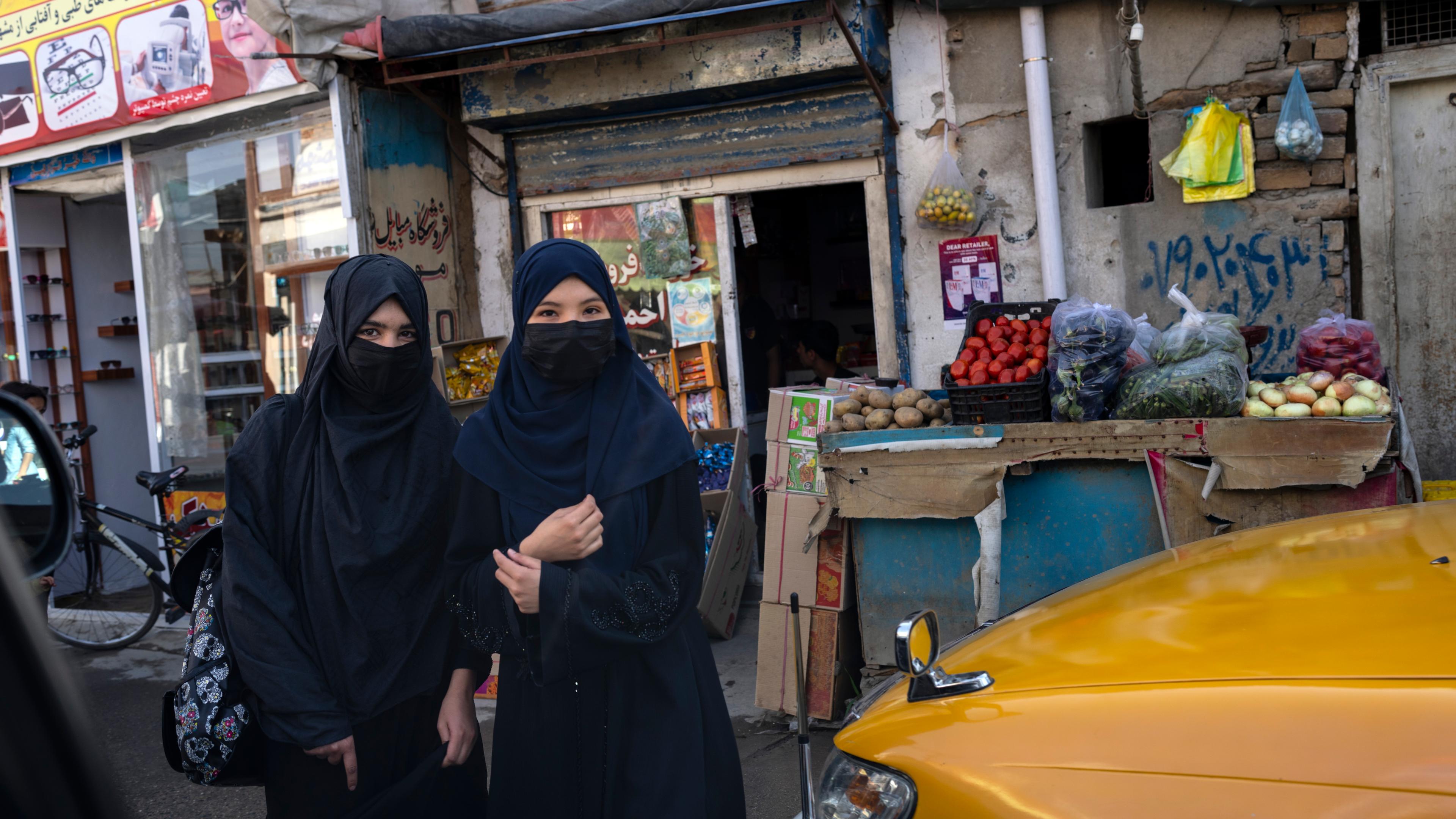 Zwei Frauen gehen in der Nähe eines Straßenmarktes spazieren in Kabul, Afghanistan.