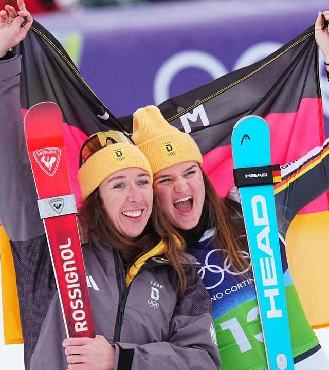 Emma Aicher und Kira Weidle-Winkelmann jubeln über ihre Silbermedaille am 10.02.2026 in Cortina D'ampezzo.