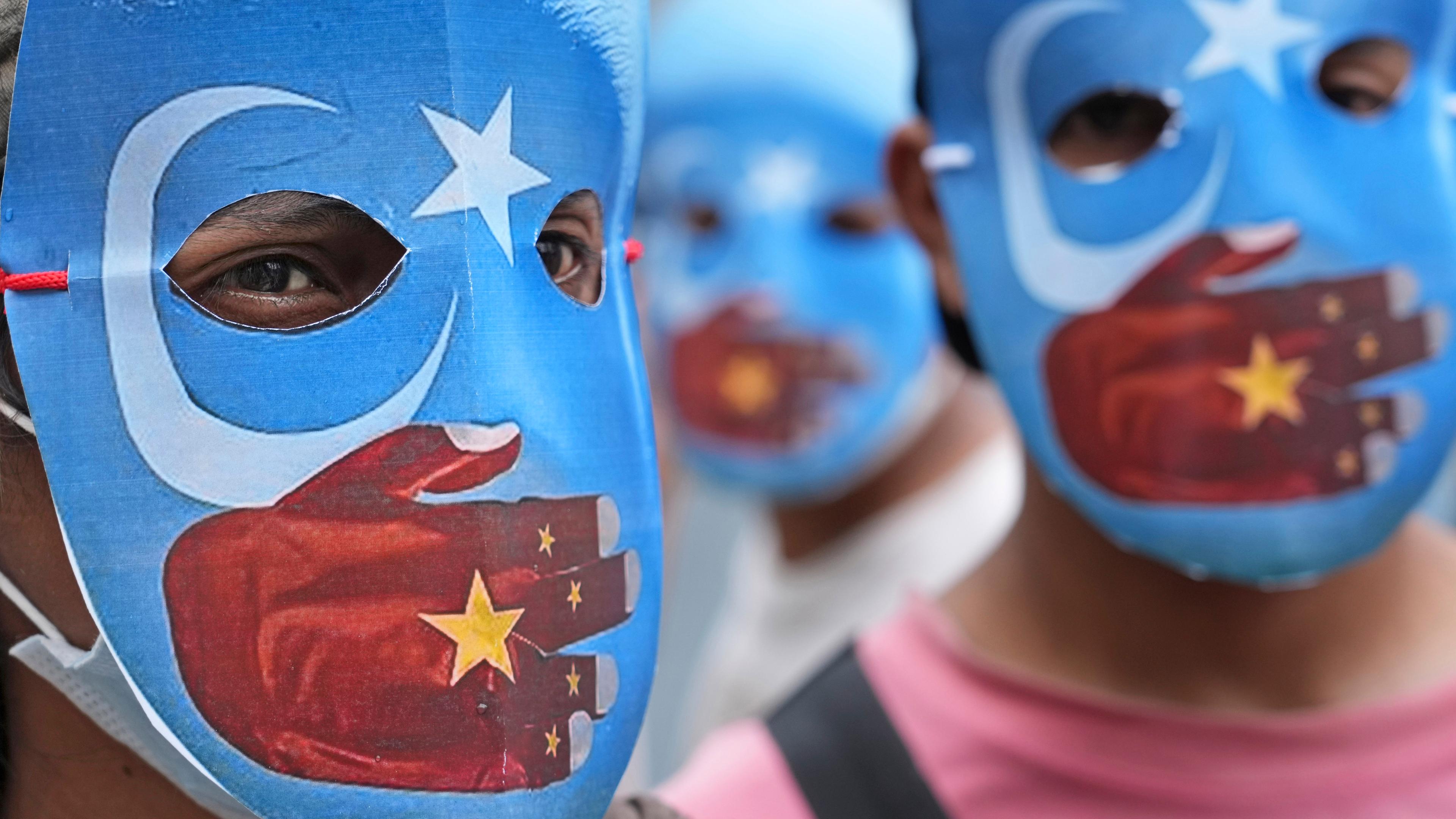 Demonstranten gegen die Olympischen Winterspiele mit Masken der Flagge von Ostturkestan 2022