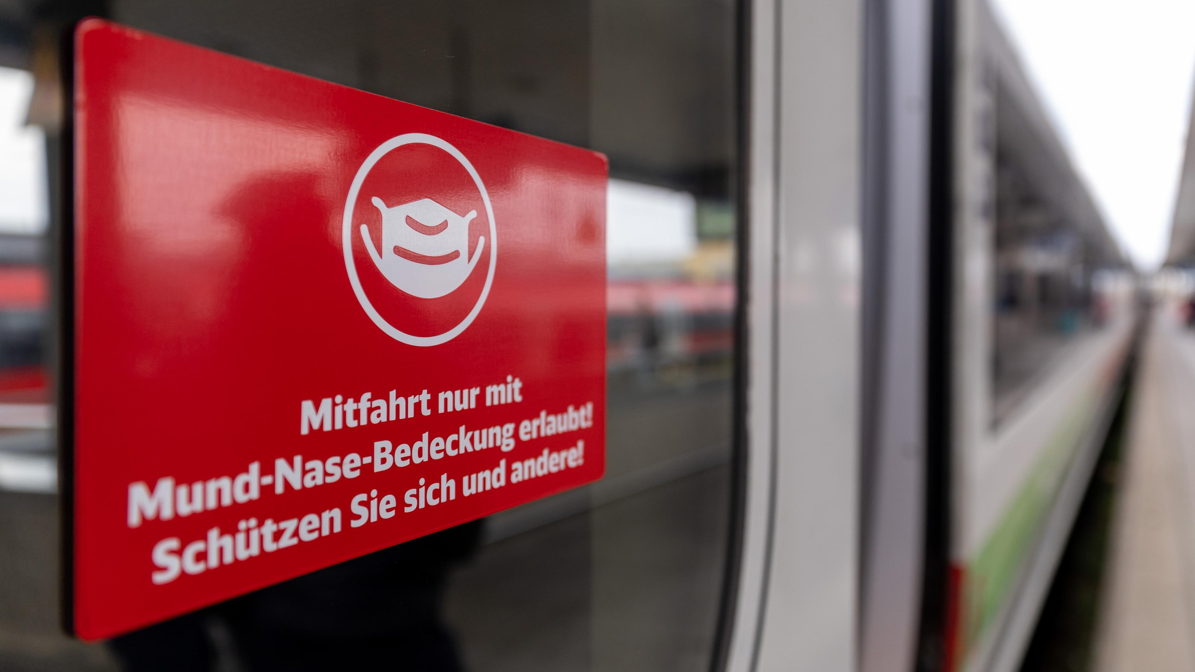 Ein Schild mit der Aufschrift "Mitfahrt nur mit Mund-Nase-Bedeckung erlaubt! Schützen Sie sich und andere!" klebt an der Zugtür eines ICE der Deutschen Bahn (DB) im Hauptbahnhof Nürnberg.