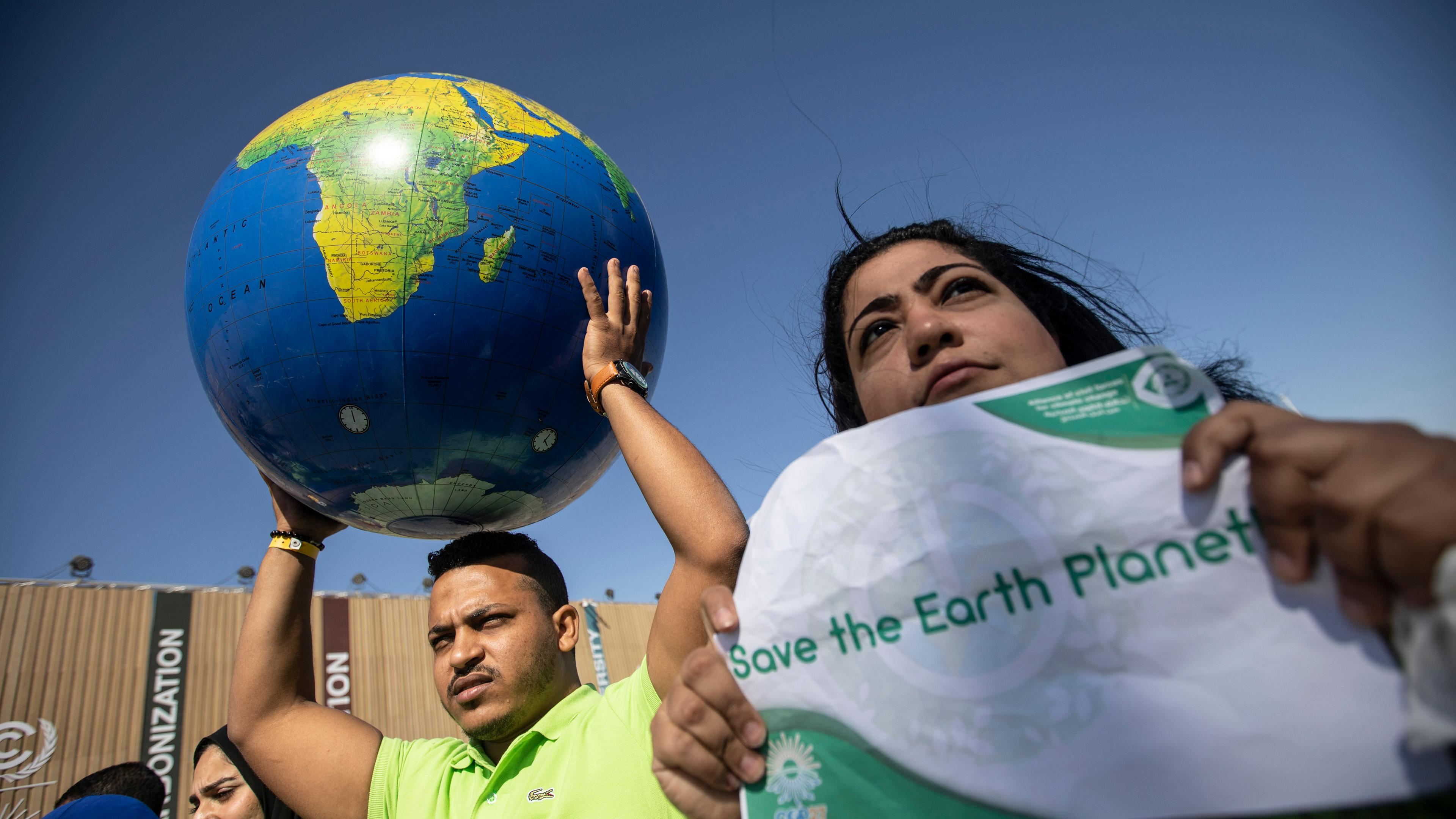 Am Rande der UN-Weltklimakonferenz COP27 halten Demonstranten eine Weltkugel hoch und rufen Slogans während einer Demonstration der ägyptischen Allianz der zivilen Kräfte für den Klimawandel.